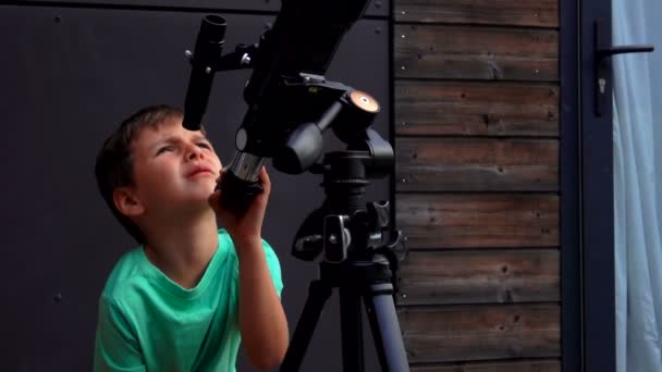 Petit garçon examine le ciel à travers un télescope — Video