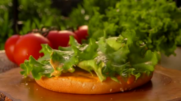 Leaf of lettuce falls onto a bun with sauce