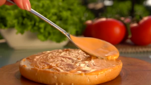 Κουτάλι επιχρίσματα την σάλτσα επάνω σε ένα κουλούρι χάμπουργκερ — Αρχείο Βίντεο