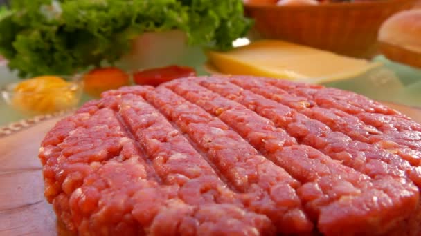 Бургер с сырой говядиной лежит на деревянной доске крупным планом — стоковое видео