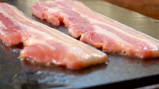 Två remsor av rå bacon rostas av grillen — Stockvideo
