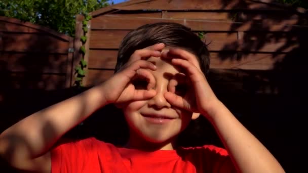 Kleiner Junge bastelt Ferngläser mit den Fingern — Stockvideo
