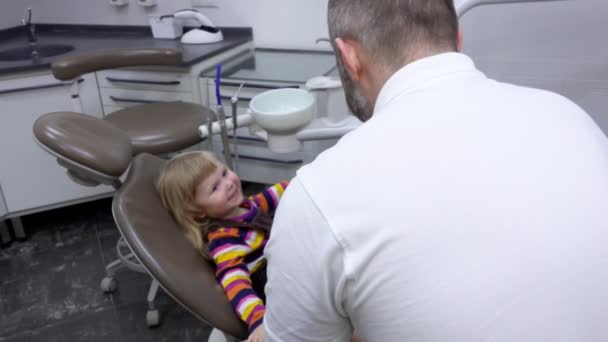 Menina está sentada em uma cadeira de dentista e mostrando dentes — Vídeo de Stock