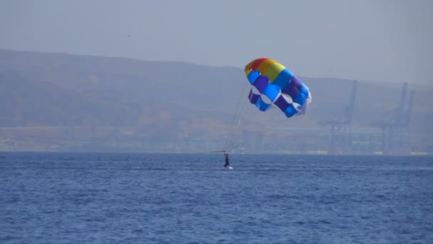 Homme volant sur un parachute spécial au-dessus de la mer — Video