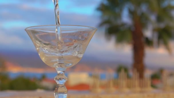 Мартини наливают в стакан на фоне моря — стоковое видео