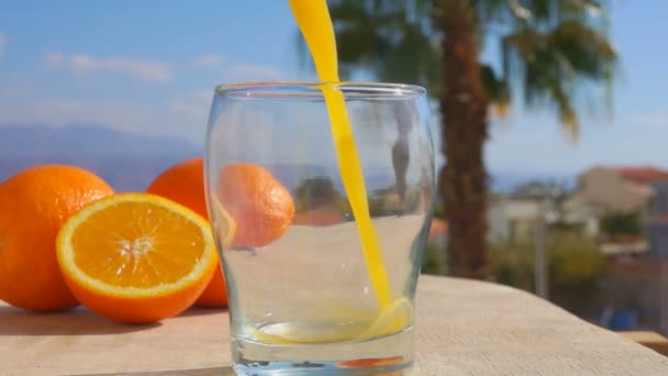 Γκρο πλαν χυμό πορτοκαλιού χύνεται ένα ποτήρι — Αρχείο Βίντεο