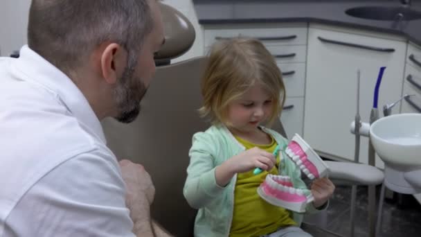 Küçük kız dişlerini nasıl fırçaladığını gösteriyor. — Stok video