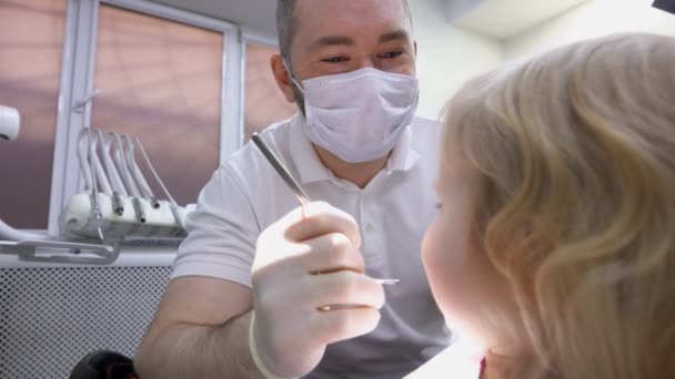 Il dentista esamina i denti di un bambino con uno specchio — Video Stock