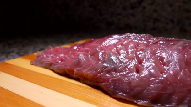 Salt falls on raw tuna lying on a board — Stock Video