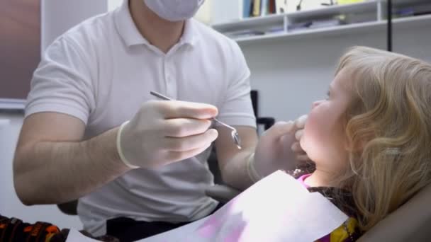 Дитина відкриває рот, щоб зубний лікар перевірив зуби — стокове відео