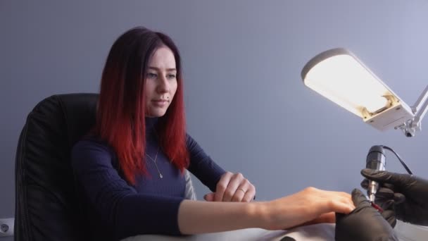 Fille aux cheveux colorés s'assoit dans une chaise dans un salon de ongles — Video