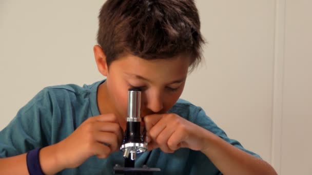 Boy picks up the lens of the microscope — Stock Video