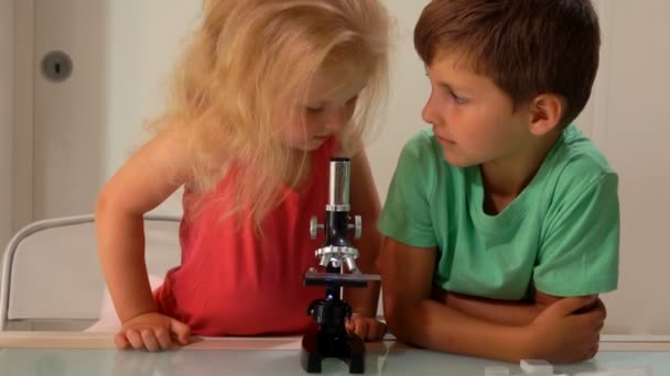 Маленькая девочка смотрит в микроскоп — стоковое видео
