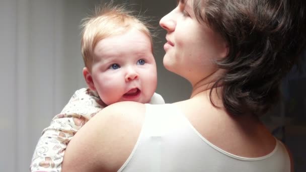 Carino bambino dagli occhi azzurri sorridente alle braccia mamme — Video Stock