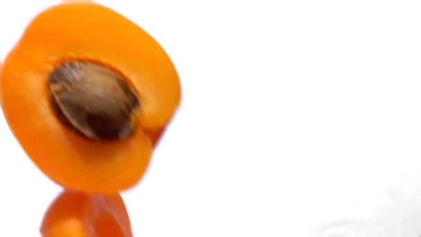 Halves ripe apricots fly on white background — Stock Video