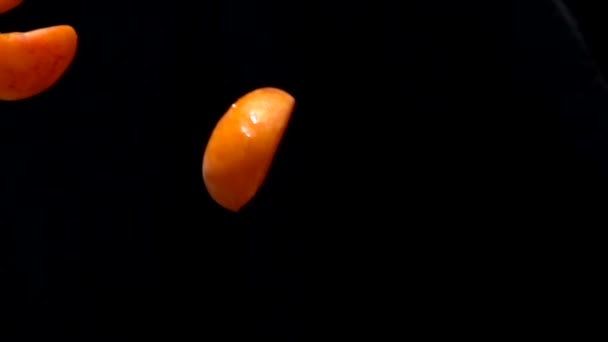 Половина спелых абрикосов летит на черном фоне — стоковое видео