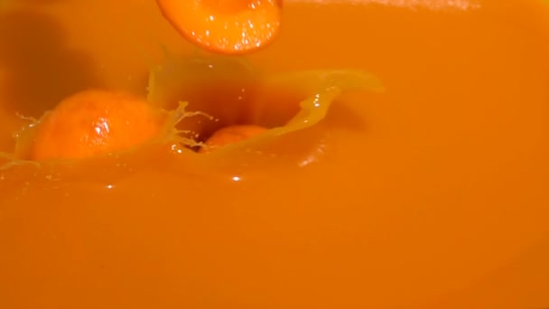 Halves ripe apricots fall into juice — Stock Video