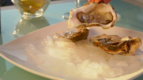 Female hand puts open oyster on a plate with ice. — Stock Video