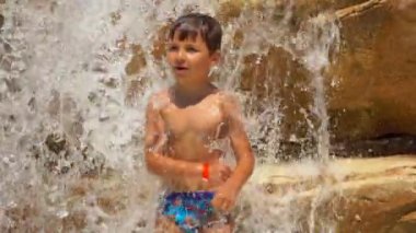 Çocuk havuzdaki kayalıklarda dans ediyor.