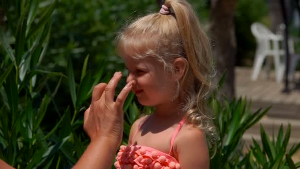Χέρι επιχρίσματα προστατευτική κρέμα στα κορίτσια πρόσωπο — Αρχείο Βίντεο