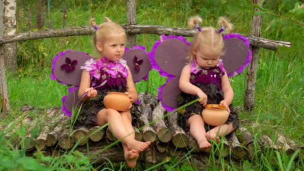 Mädchen mit Schmetterlingsflügeln essen Honig aus Töpfen — Stockvideo