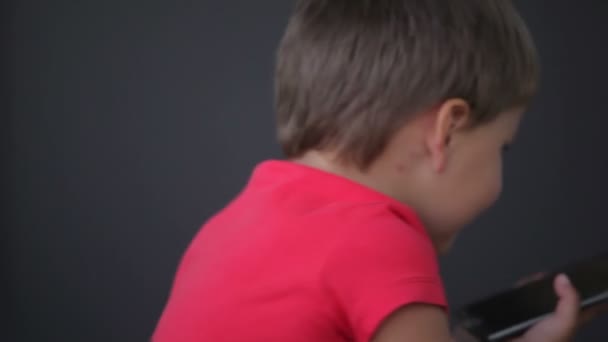 Pequeño niño lindo juega con un teléfono móvil — Vídeos de Stock