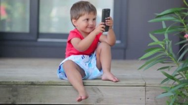 Küçük sevimli çocuk cep telefonu ile bir fotoğraf çeker