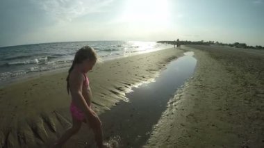 Küçük kız annesine sarılmak için kıyı şeridi boyunca koşar.