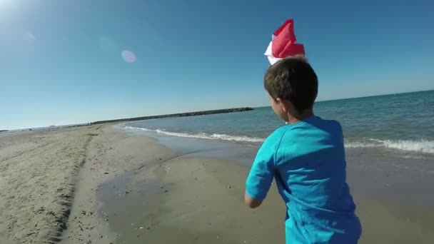 Chlapce vede podél pláže s vlajkou — Stock video