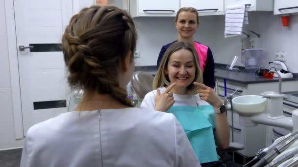 Mulher sorri alegremente e fala com seu dentista — Vídeo de Stock