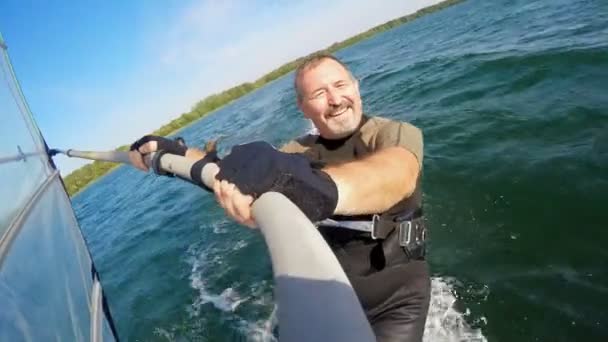 Adam bir göl üzerinde bir rüzgar sörfü tahtası üzerinde yelken gider — Stok video