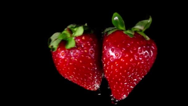Strawberries collide and rotate on black background — Stock Video