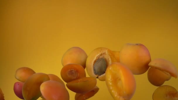 Сочный абрикос наполовину отскакивает на желтом фоне — стоковое видео