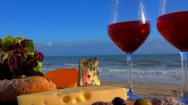 Kırmızı şarap ve peynirli deniz kenarında romantik bir piknik.