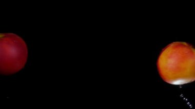 Şeftaliler çarpışıyor. Siyah zeminde su sıçrıyor.