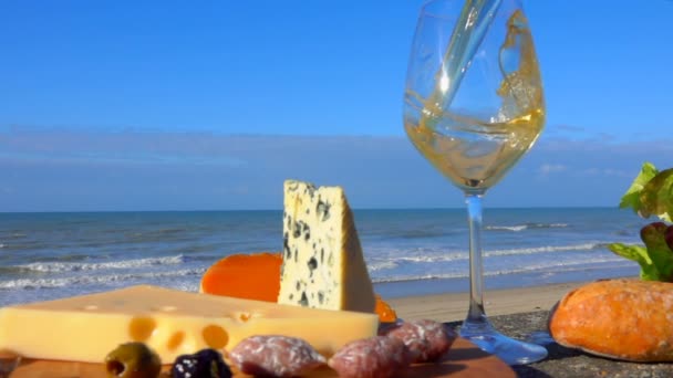 Białe wino wlewa się do szklanki obok sera. — Wideo stockowe