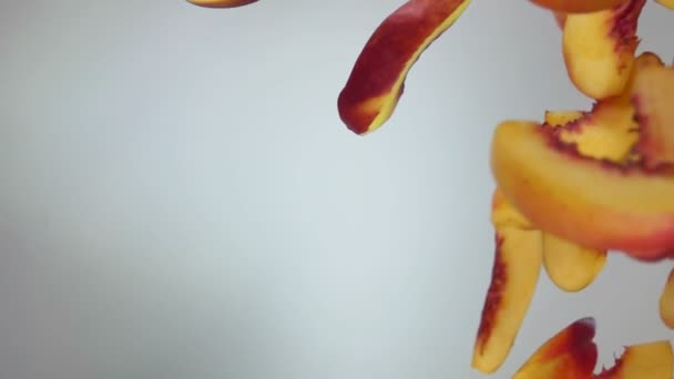 Pfirsichscheiben fliegen auf weißem Hintergrund herunter — Stockvideo