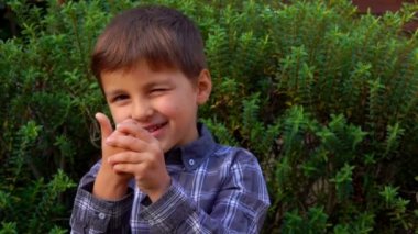 Neşeli çocuk parmaklarını 10 'a kadar sayıp gözlerini kısıyor.