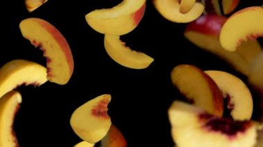 Şeftali dilimleri siyah arka planda uçar.