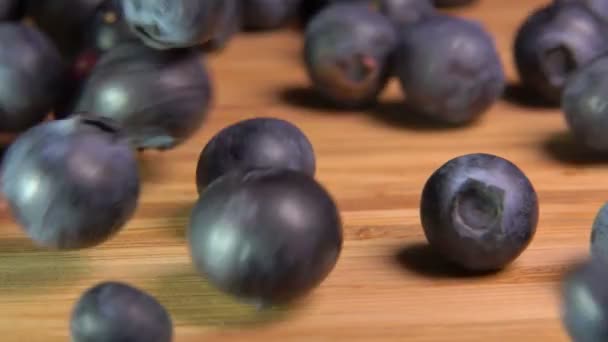 Große Blaubeeren fallen und hüpfen auf Holzoberfläche — Stockvideo