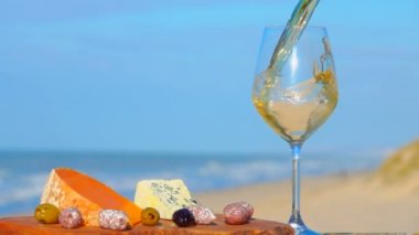 Beyaz şarap peynirin yanında bardağa dökülür, zeytinler