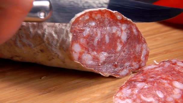 Сухая колбаса в белой коже режется ножом — стоковое видео