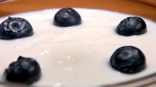 Grandes arándanos deliciosos caen sobre el yogur — Vídeos de Stock