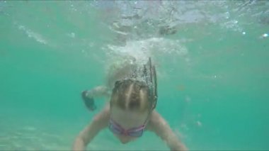 Yüzme gözlüklü küçük kız suyun altına dalıyor.