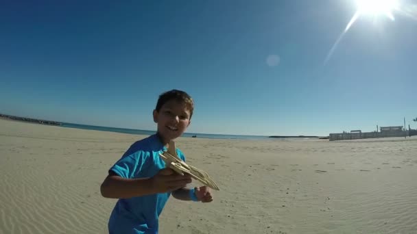 Glad pojke leker med modell flygplan på stranden — Stockvideo