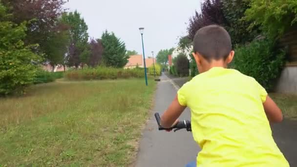 Junge im gelben T-Shirt fährt Fahrrad im Park — Stockvideo