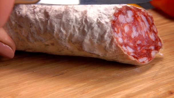 Нож режет сухую колбасу белой кожей на куски — стоковое видео