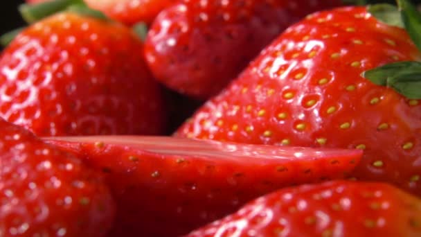 Aufgeschnittenes Stück Erdbeeren fällt auf rote Beeren — Stockvideo