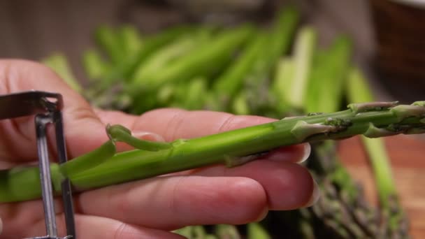 Нож очищает стебель зеленой спаржи от кожи — стоковое видео