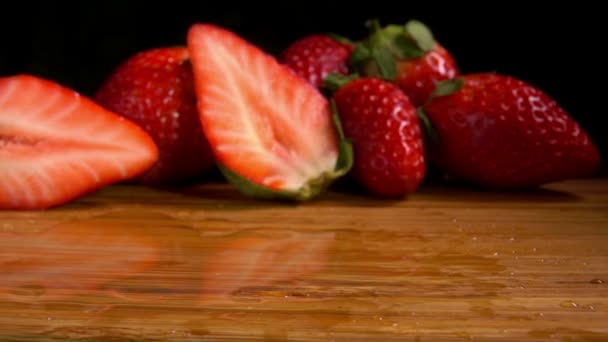 Fraises sucrées mûres tombent sur une planche de bois humide — Video